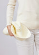 Model folding white sun hat to show that it's packable 