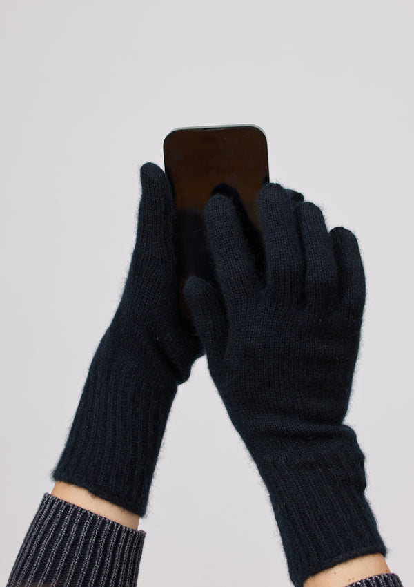 Model wearing black cashmere texting glove and holding phone