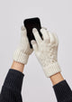 Model wearing ivory knit touch screen gloves and holding a phone