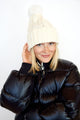 Cable knit beanie with pom on model wearing black coat