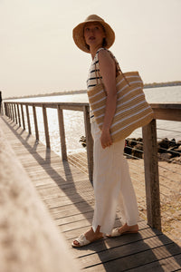 Model wearing white striped straw tote bag