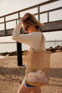 Model wearing natural straw fisherman bag