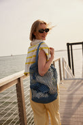 Model holding blue straw fisherman bag