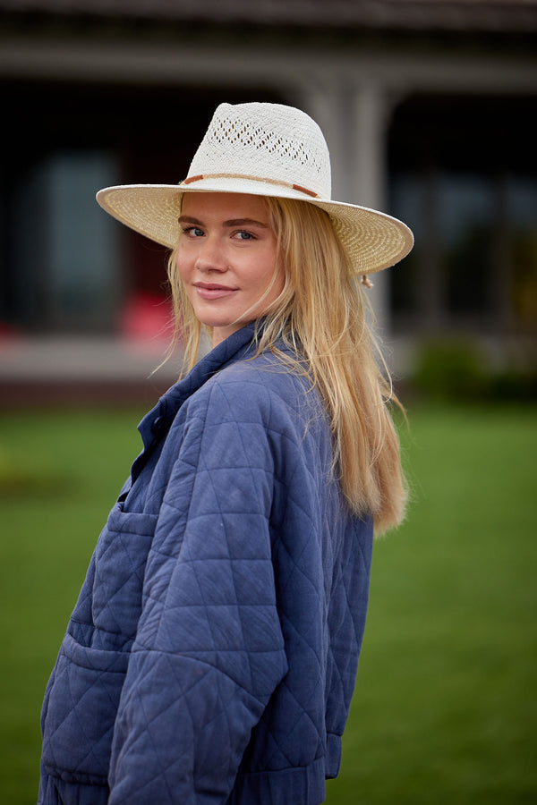 Model wearing a white straw hat and blue jacket