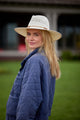 Model wearing a white straw hat and blue jacket
