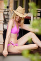 Model wearing pink bikini and straw hat with colorful trim