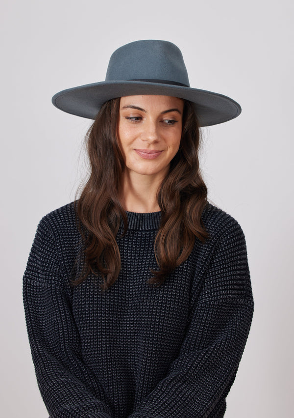 Model wearing dusty blue felt brimmed hat and charcoal sweater