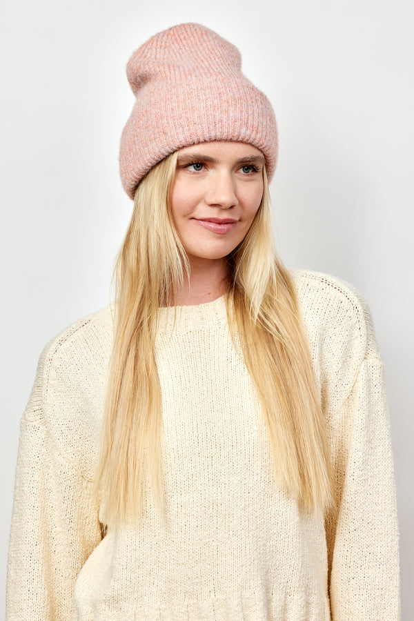 Model looking to her left and wearing light pink cuff beanie