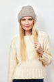 Model wearing taupe beanie and holding hair