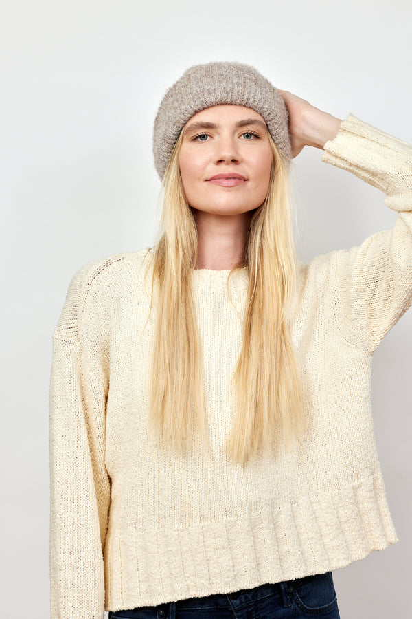 Model wearing taupe cuffed beanie and ivory sweater