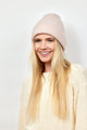 Model smiling and wearing light pink textured knit cuffed beanie