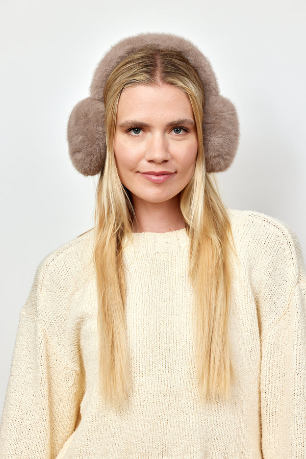 Model wearing taupe faux fur earmuffs and looking at camera