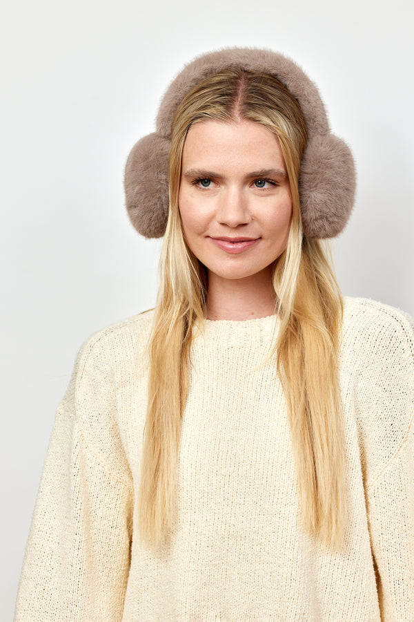 Model wearing taupe faux fur earmuffs and ivory sweater