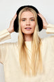 Model looking at camera and wearing black faux fur earmuffs