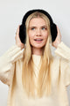 Molding wearing black faux fur earmuffs and ivory sweater