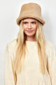 Model wearing tan faux fur bucket hat and looking to her right