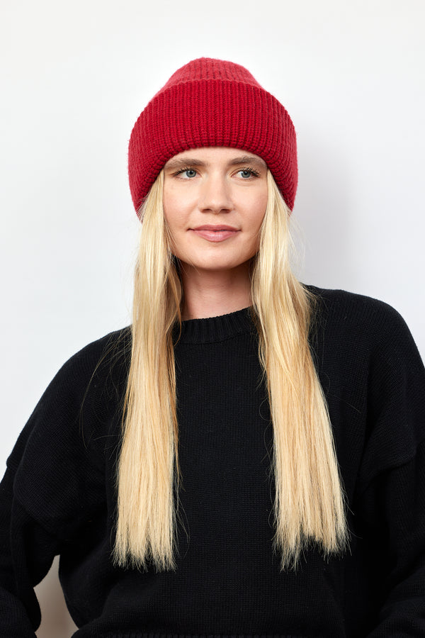 Model wearing red knit cuffed beanie and black sweater