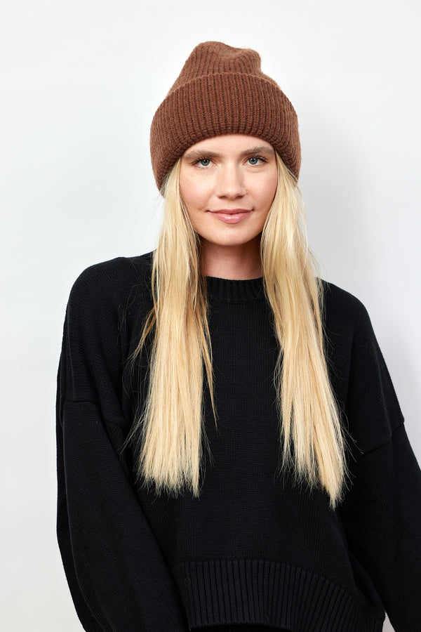 Model wearing brown knit cuffed beanie and looking at camera