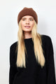 Model wearing brown knit cuffed beanie and black sweater