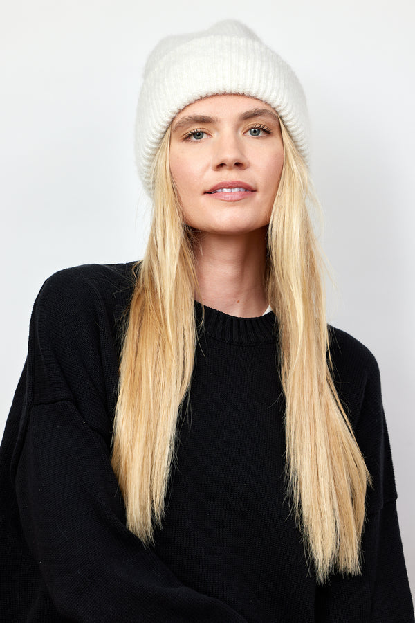 Model wearing ivory ribbed knit beanie and black sweater