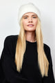 Model wearing ivory ribbed knit beanie and black sweater