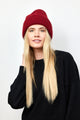 Berry red ribbed knit beanie on model touching her hair