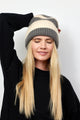 Grey and ivory striped ribbed knit cuffed beanie on model with hand on her head