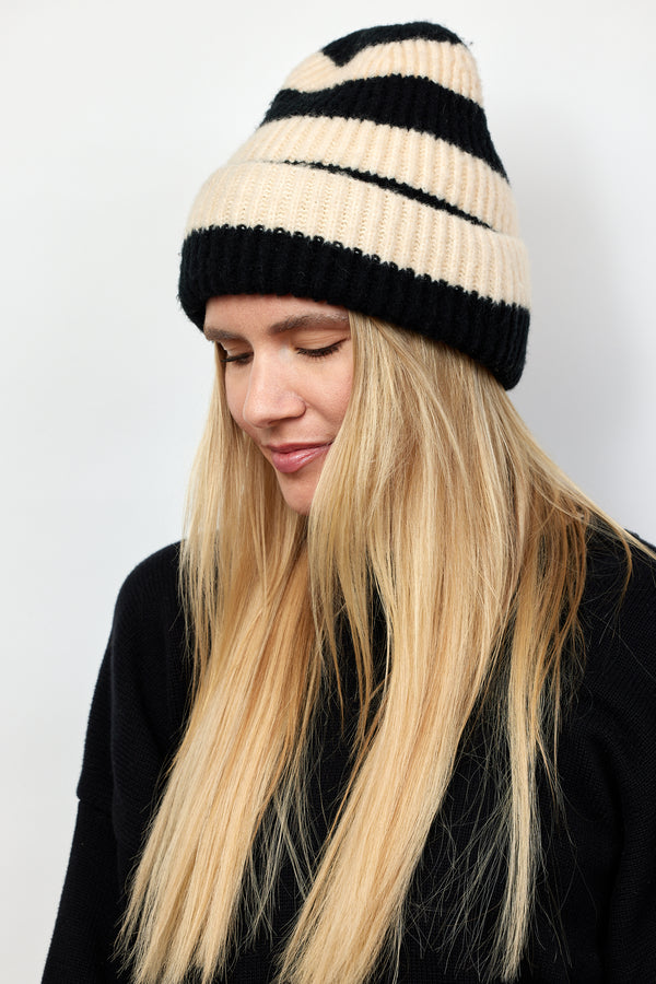 Black and ivory striped ribbed knit cuffed beanie on model wearing black sweater