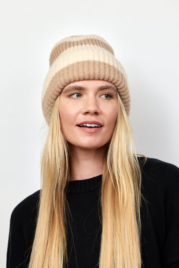 Tan and ivory striped ribbed knit cuffed beanie on model wearing black sweater