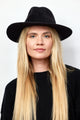 Model wearing black velour brimmed hat and black sweater