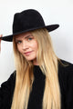 Model holding brim of black velour brimmed hat