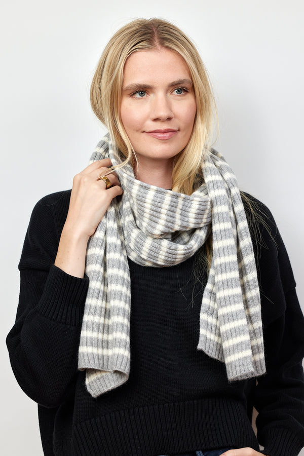 Model holding grey and ivory ribbed striped scarf wrapped around her neck