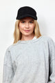 Model wearing black sherpa baseball cap and grey sweatshirt