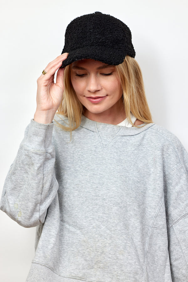 Model holding brim of black sherpa baseball cap