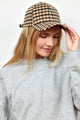 Model holding brim of ivory and brown checkered baseball hat