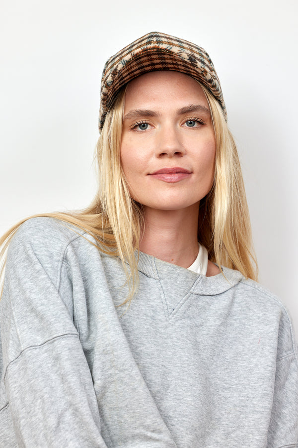 Model wearing brown and ivory checkered baseball cap