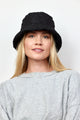 Model wearing black quilted bucket hat while looking at camera