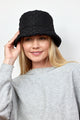 Model wearing black quilted bucket hat with faux fur lining