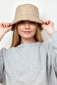 Model holding brim of tan quilted bucket hat with faux fur lining