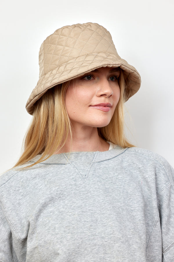 Model wearing tan quilted bucket hat on model