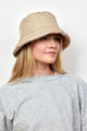 Model wearing tan quilted bucket hat with faux fur lining