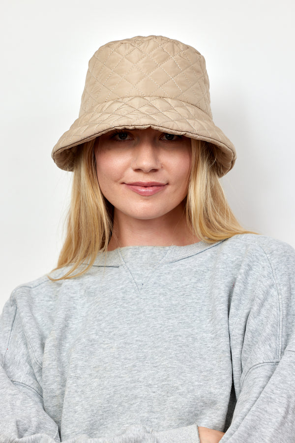 Model wearing tan quilted bucket hat and grey sweatshirt