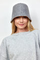 Model wearing grey knit bucket hat and grey sweatshirt with blonde hair