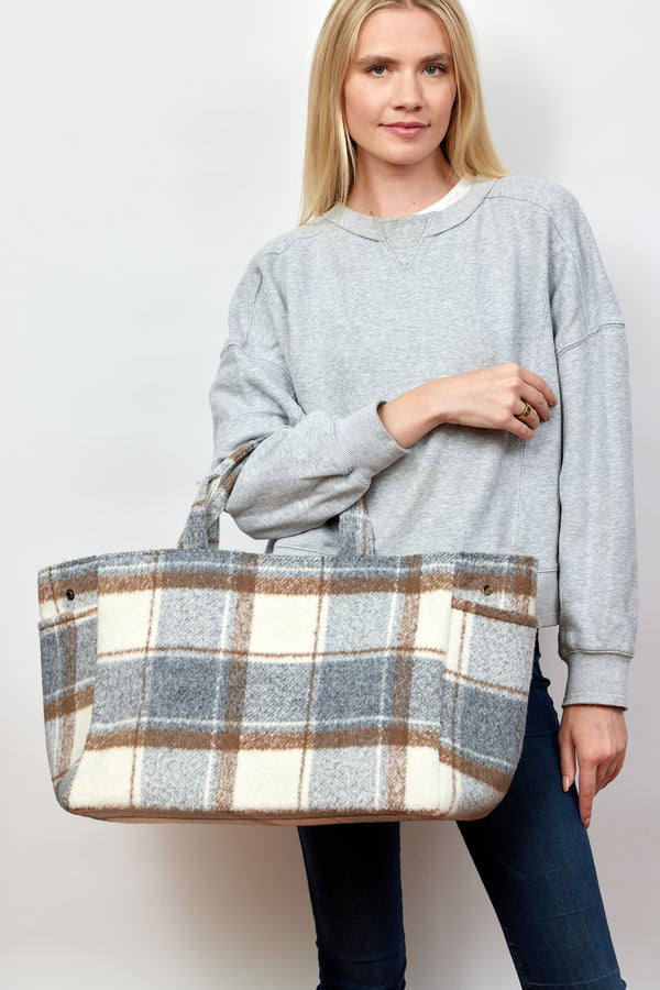 Model holding ivory and grey plaid tote