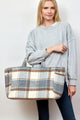 Model holding ivory and grey plaid tote