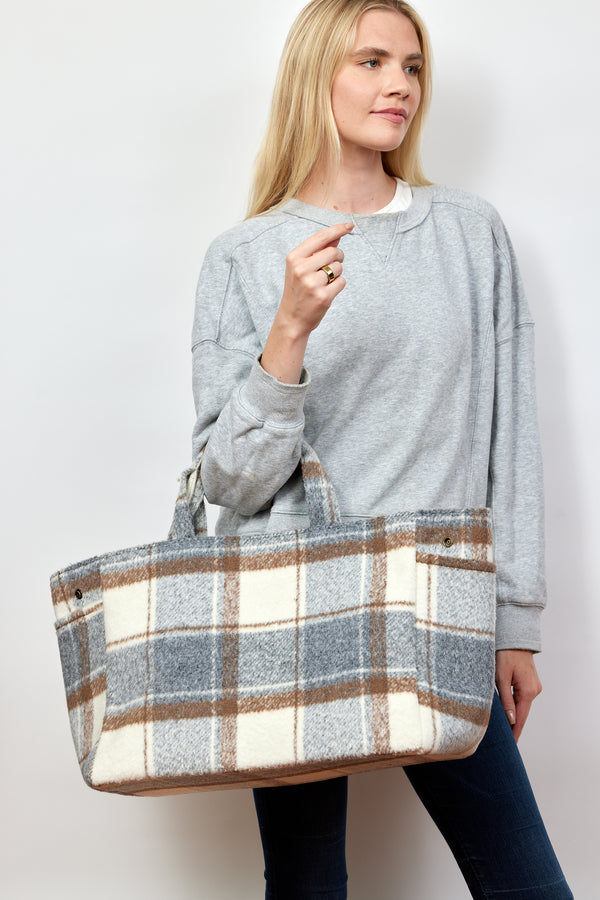 Model wearing grey sweatshirt and holding grey and ivory plaid tote