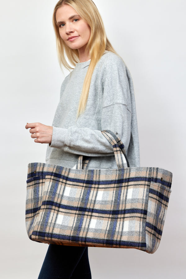 Model holding blue and brown plaid tote