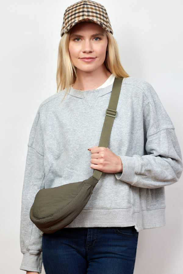 Model wearing olive nylon crossbody bag and checkered baseball cap