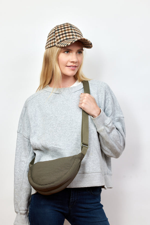 Model wearing olive nylon crossbody bag and holding strap