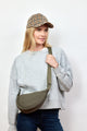 Model wearing olive nylon crossbody bag and holding strap